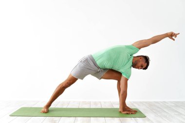 Beyaz arka planda yoga yapan yakışıklı bir genç.