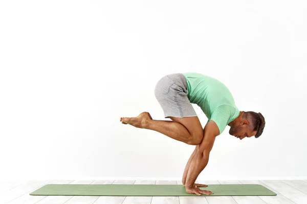 Man berlatih keseimbangan yoga berpose pada latar belakang studio putih — Stok Foto