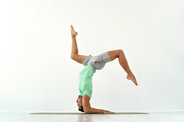 Jovem acrobacias ginástica fazendo um estúdio de suporte isolado no fundo branco, atleta esportivo — Fotografia de Stock