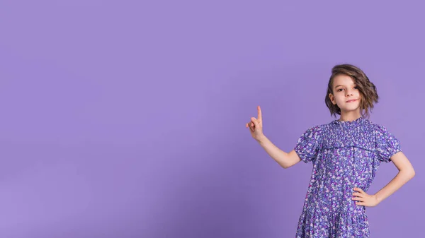 Look There. Excited Caucasian Kid Girl Pointing Thumb At Free Space For Text Posing On Purple Studio Background. Panorama — Stock Photo, Image