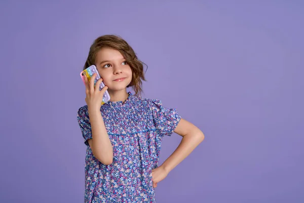 Little girl holding telephone isolated over violet color background — Stock Photo, Image