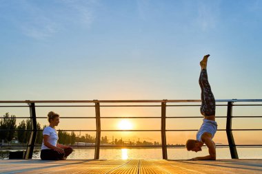 Çiftler doğada birlikte yoga yapıyorlar. Sabah egzersizleri gün doğumunda..