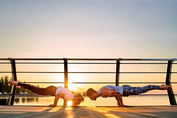 Pár cvičí jógu spolu venku na přírodě. Ranní cvičení při východu slunce. — Stock fotografie