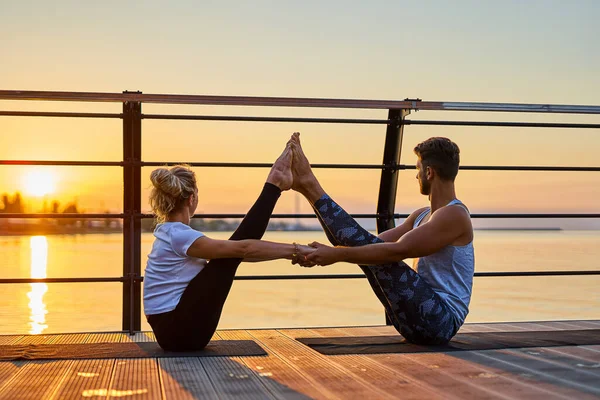 Ajuste pareja joven haciendo acro yoga en el muelle junto al mar. Estilo de vida saludable. Gente al aire libre actividad deportiva en vacaciones familiares —  Fotos de Stock