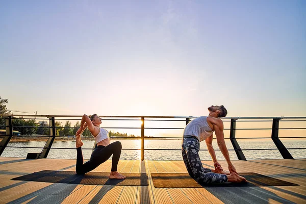 Pareja haciendo yoga juntos en la naturaleza al aire libre. Ejercicios matutinos al amanecer. —  Fotos de Stock