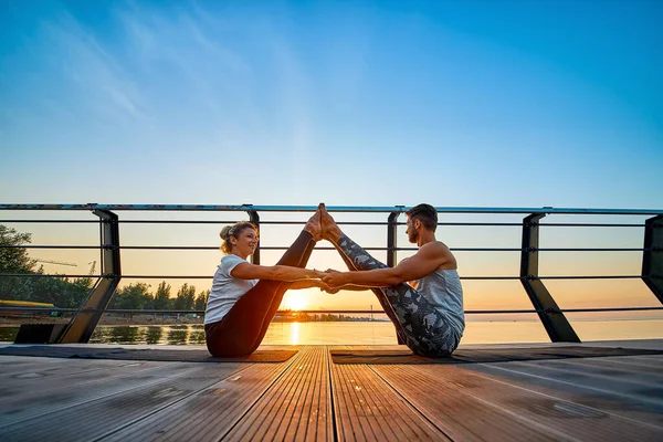 Ajuste pareja joven haciendo acro yoga en el muelle junto al mar. Estilo de vida saludable. Gente al aire libre actividad deportiva en vacaciones familiares —  Fotos de Stock