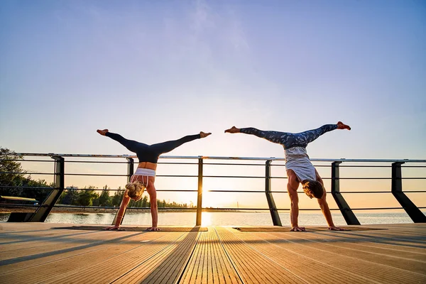 Pareja haciendo yoga juntos en la naturaleza al aire libre. Ejercicios matutinos al amanecer. —  Fotos de Stock