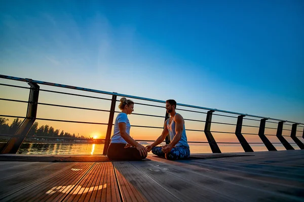 Adatto a giovani coppie che fanno yoga, posa di loto. Uno stile di vita sano. Persone attività sportive all'aperto in vacanza in famiglia — Foto Stock