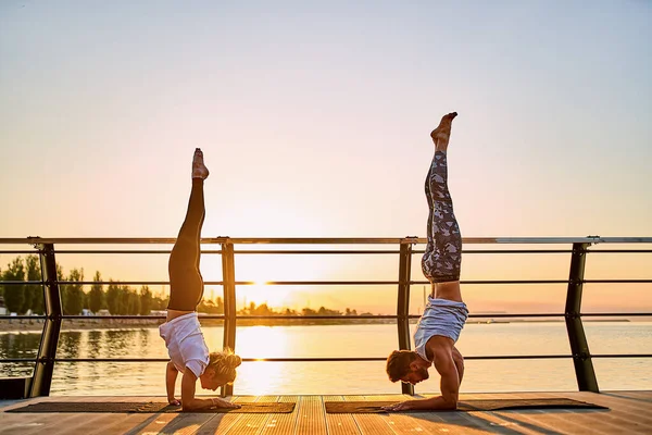 Pareja haciendo yoga juntos en la naturaleza al aire libre. Ejercicios matutinos al amanecer. —  Fotos de Stock