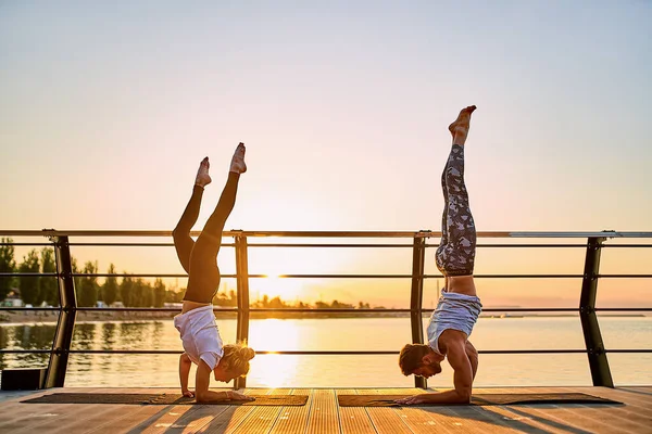 Couple pratiquant le yoga ensemble sur la nature à l'extérieur. Exercices matinaux au lever du soleil. — Photo