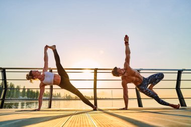 Çiftler doğada birlikte yoga yapıyorlar. Sabah egzersizleri gün doğumunda..
