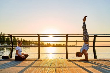 Çiftler doğada birlikte yoga yapıyorlar. Sabah egzersizleri gün doğumunda..