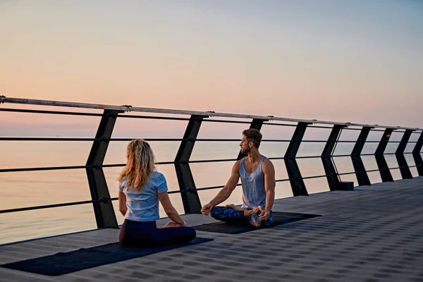 Ajuste pareja joven haciendo yoga, pose de loto. Estilo de vida saludable. Gente al aire libre actividad deportiva en vacaciones familiares —  Fotos de Stock