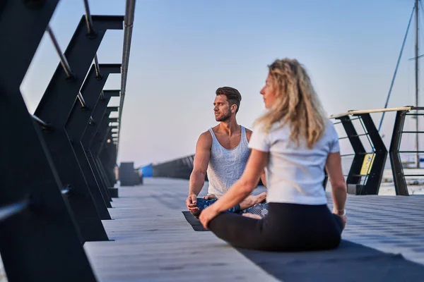 Ajuste pareja joven haciendo yoga, pose de loto. Estilo de vida saludable. Gente al aire libre actividad deportiva en vacaciones familiares —  Fotos de Stock