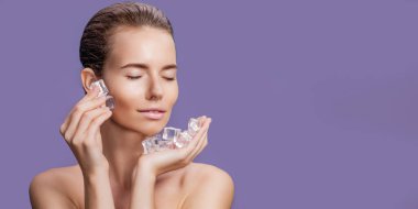 Yüzünün yanında buz küpleri tutan doğal makyajlı güzel bir kadın.