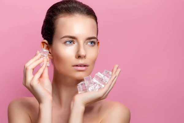 Mooie vrouw met natuurlijk uitziende make-up houden ijsblokjes in de buurt gezicht — Stockfoto