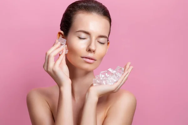 Mooie vrouw met natuurlijk uitziende make-up houden ijsblokjes in de buurt gezicht — Stockfoto