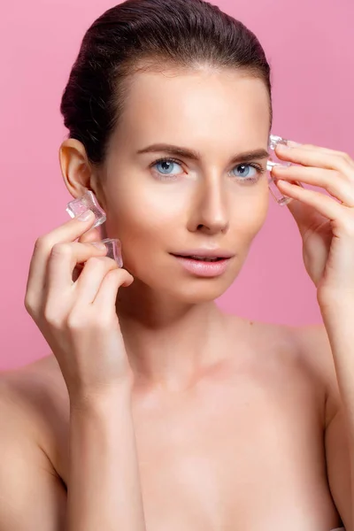 Mooie vrouw met natuurlijk uitziende make-up houden ijsblokjes in de buurt gezicht — Stockfoto