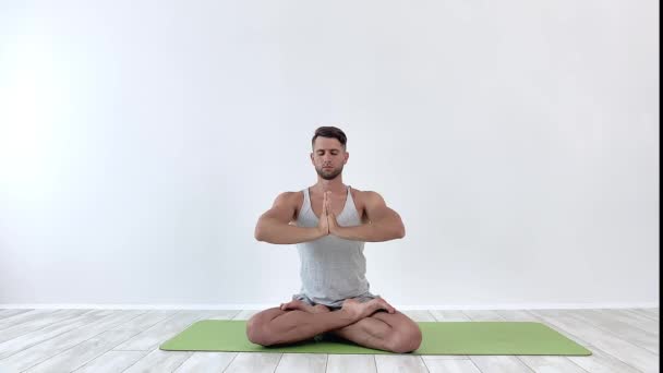 Yoga masculin médite dans la pose classique en studio sur fond blanc — Video