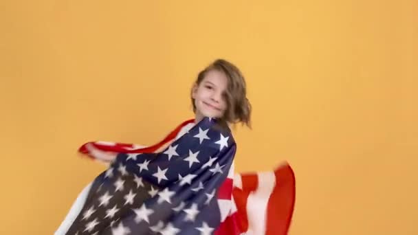 Hazafias ünnep. Boldog gyermek, aranyos lány amerikai zászló sárga stúdió háttér. Amerika július 4-ét ünnepli, a függetlenség napját. — Stock videók