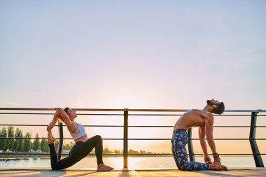 Çiftler doğada birlikte yoga yapıyorlar. Sabah egzersizleri gün doğumunda..