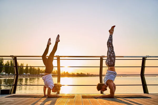 Pareja haciendo yoga juntos en la naturaleza al aire libre. Ejercicios matutinos al amanecer. —  Fotos de Stock