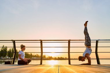 Çiftler doğada birlikte yoga yapıyorlar. Sabah egzersizleri gün doğumunda..