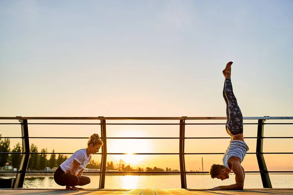 Pareja haciendo yoga juntos en la naturaleza al aire libre. Ejercicios matutinos al amanecer. —  Fotos de Stock