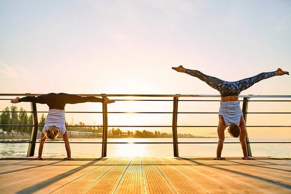 Pareja haciendo yoga juntos en la naturaleza al aire libre. Ejercicios matutinos al amanecer. —  Fotos de Stock