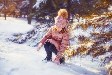 Küçük kız güneşli kış gününde eğleniyor.