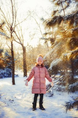 Küçük kız güneşli kış gününde eğleniyor.