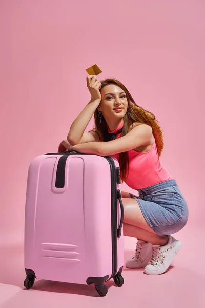 Tourist woman in summer casual clothes on pink background holding credit card. — Stockfoto