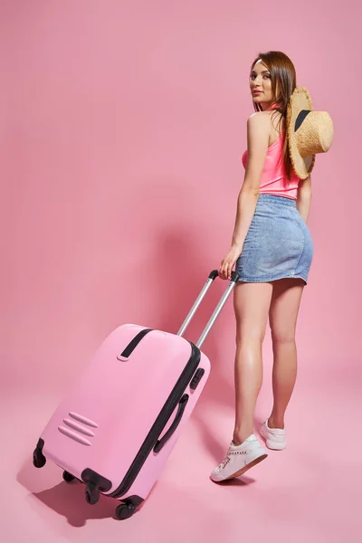 Turistka v létě ležérní oblečení na růžovém pozadí držení kreditní karty. — Stock fotografie