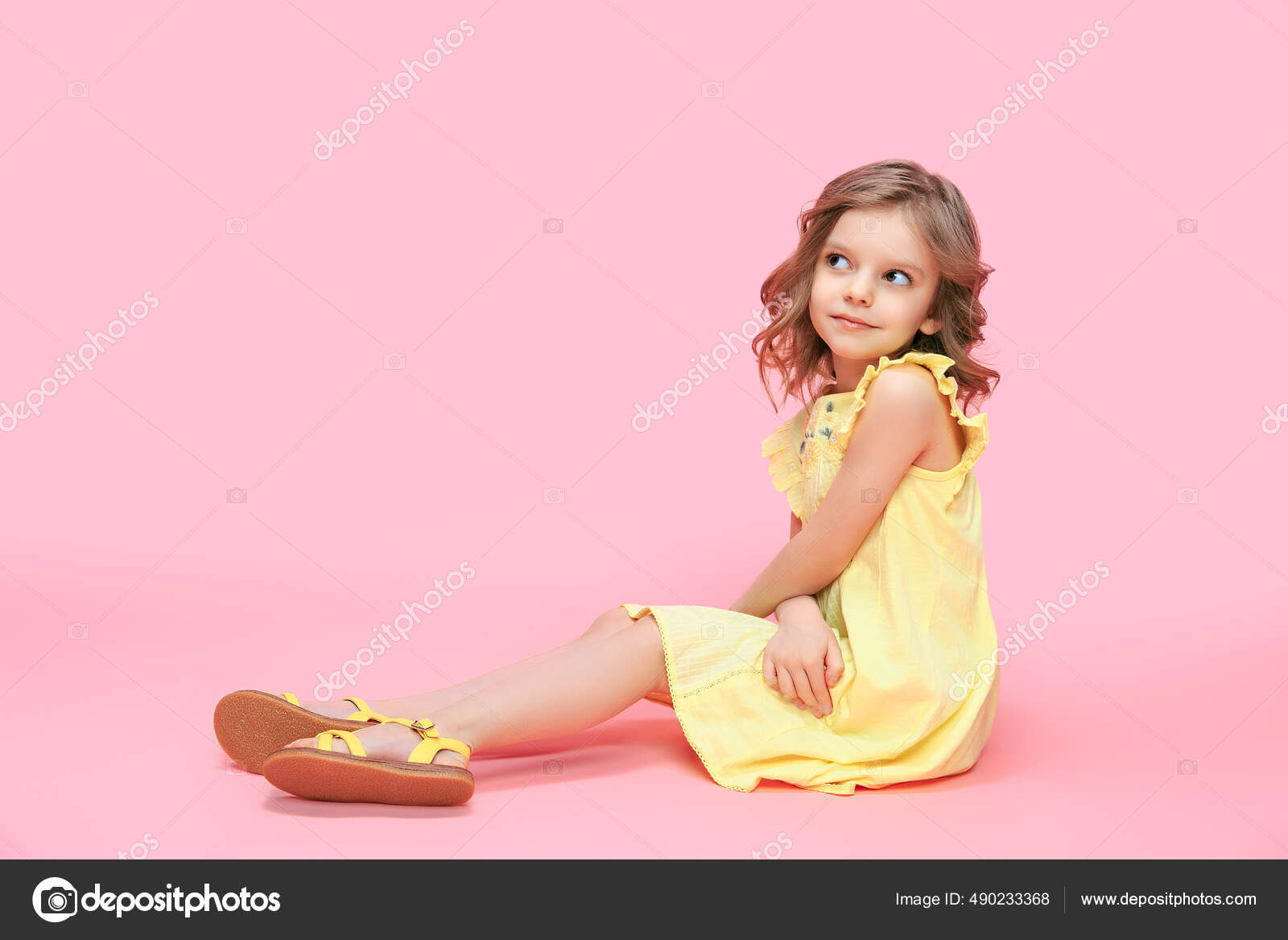 Cute baby girl 45 year old wearing trendy yellow dress, sitting in