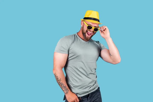 El hombre emocional barbudo muscular de moda en sombrero de paja amarillo posando en el estudio sobre fondo azul — Foto de Stock