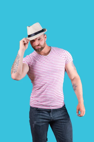 El hombre barbudo musculoso de moda en sombrero de paja posando en el estudio sobre fondo azul —  Fotos de Stock