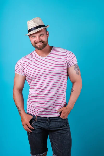 ファッショナブルな筋肉ひげそり笑顔男でわら帽子でスタジオで青の背景 — ストック写真