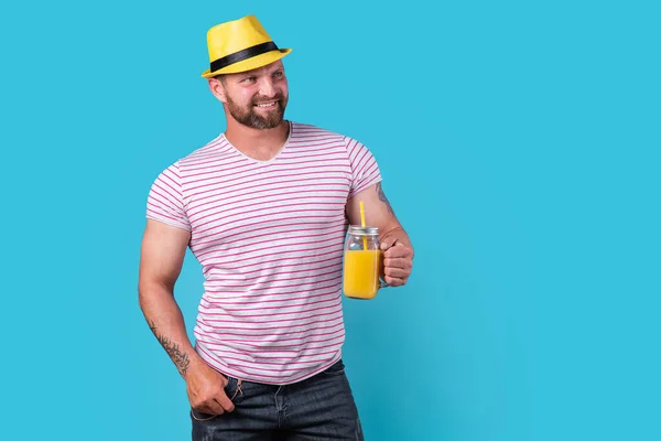 Creatieve man in zonnebril en zomerkleding, stijlvolle hoed die ontspannen staat en drinkt uit creatieve cocktailfles — Stockfoto