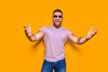 İzole edilmiş sarı arka plan üzerinde dikilmiş tişört giyen genç yakışıklı bir adam kamerayı işaret ediyor ve sen, el işareti, pozitif ve kendinden emin bir hareket.