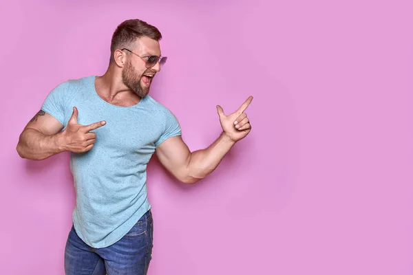 Joven hombre emocionado de vacaciones sobre fondo rosa señalando el dedo hacia un lado con una idea exitosa. — Foto de Stock