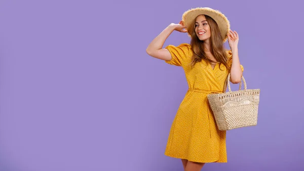 穿着黄色衣服、戴着夏草帽、头戴紫罗兰色背景的漂亮微笑的年轻女子. — 图库照片