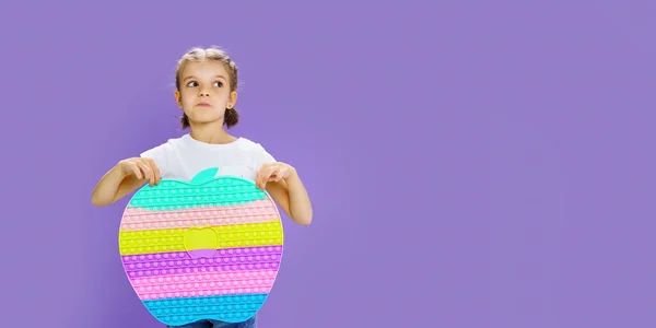 Kid holding huge apple anti stress bubble. motor skills. pop it fun. child holding color popit fidget — Stock Photo, Image