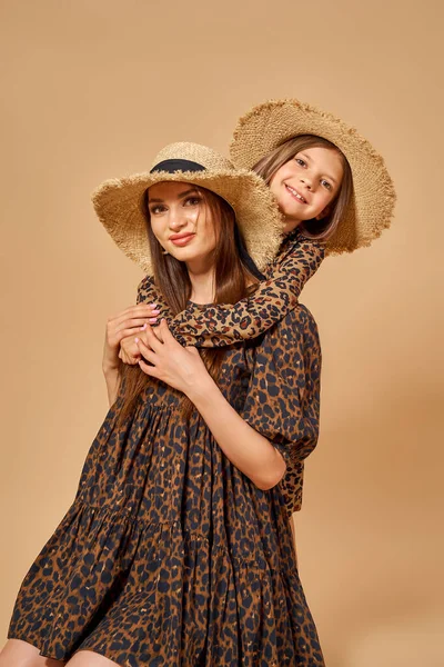 Två vackra unga flickor systrar i fina djur mönster klänningar med halm hattar poserar i studio — Stockfoto