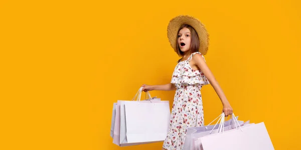 Portrait d'adolescente joyeuse dans un chapeau de paille avec des sacs à provisions lumineux sur fond jaune, espace de copie — Photo