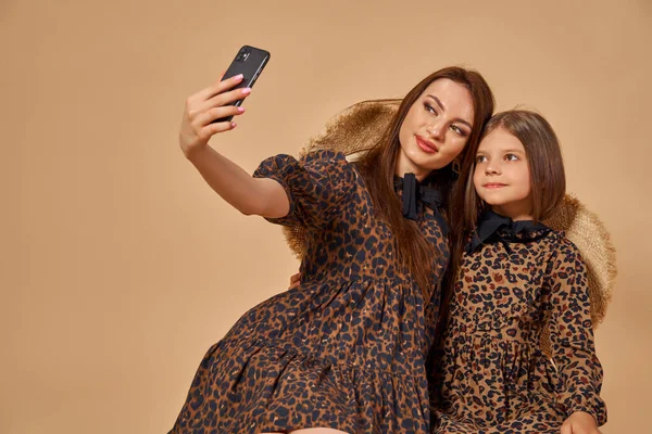 Dvě krásné mladé dívky sestry se selfie v pěkné zvířecí vzor šaty se slámou klobouky pózovat ve studiu — Stock fotografie