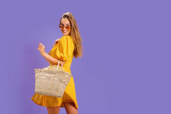 Mujer de moda en bonito vestido amarillo y bolso de paja. Moda primavera verano foto — Foto de Stock