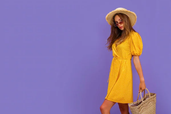Mulher bonita em vestido branco, chapéu de palha de verão, óculos de sol, saco de palha isolado em fundo violeta pastel. — Fotografia de Stock