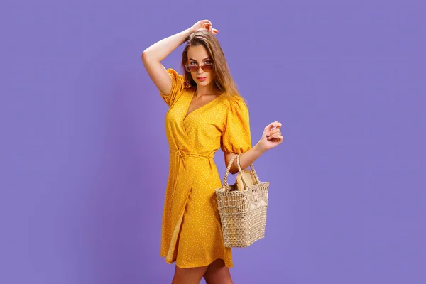 Модна жінка в гарній жовтій сукні і солом'яній сумці. Мода весна літо фото — стокове фото