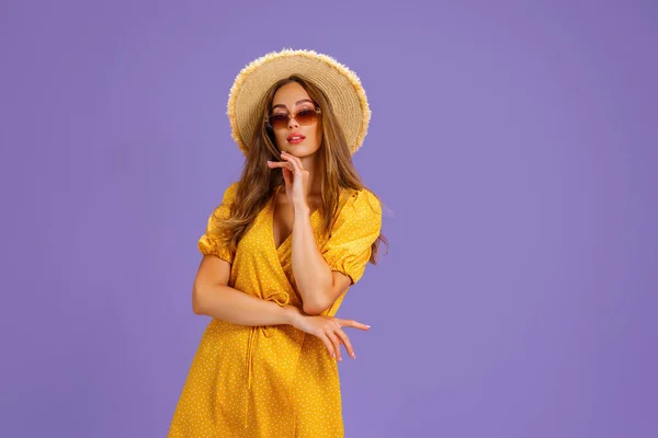 穿着黄色衣服、头戴夏帽、戴着墨红色背景的太阳镜的兴奋的年轻女子的画像. — 图库照片