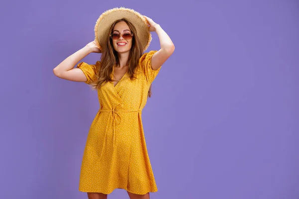 Retrato de jovem excitada em vestido amarelo, chapéu de verão, óculos de sol posando isolado no fundo violeta pastel. — Fotografia de Stock